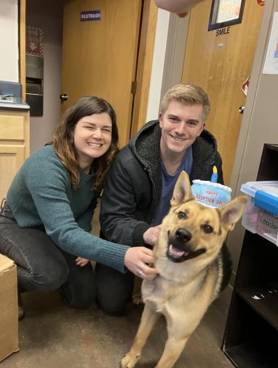 Happy couple both touching a smiling shepherd